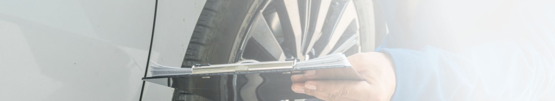 Ein Mann steht nach einem Unfall neben seinem beschädigten Fahrzeug und hält eine Zwischenablage in der Hand