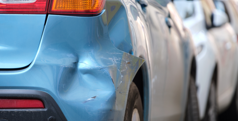 Verbeultes Auto mit beschädigtem Kotflügel, geparkt auf der Straßenseite der Stadt.