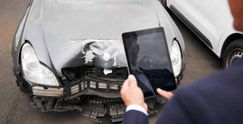 Gutachter macht ein Bild von der Front eines Unfallautos