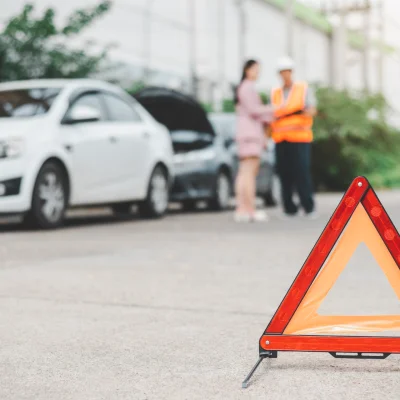Ein rotes Notfalldreieck auf der Straße weist auf einen Unfall oder eine Autopanne hin