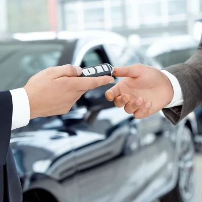 Unbekannter männlicher Autohändler übergibt Autoschlüssel an neuen Besitzer