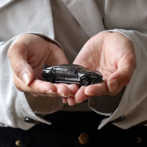 Frau von der Versicherung hält ein Spielzeugauto in der Hand