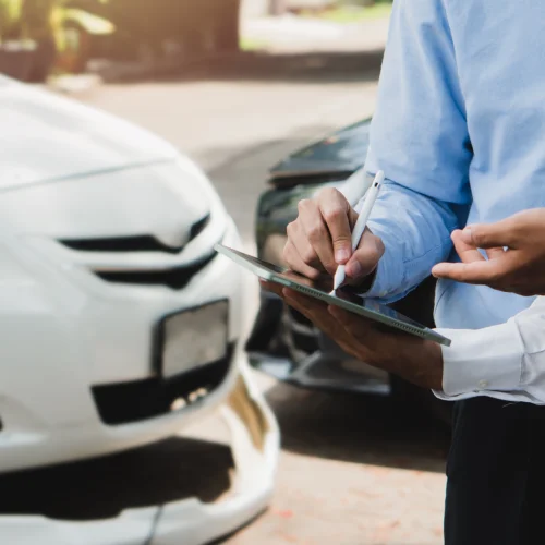 Zwei menschen gucken auf ein Tablet vor zwei Autos die einen Unfall hatten