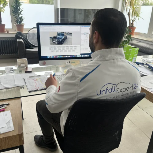 Ein Unfallgutachter von UnfallExpert24 sitzt am Schreibtisch und erstellt ein Gutachten am Computer