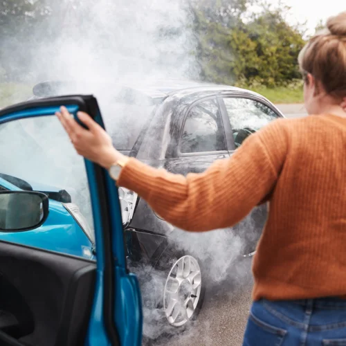 Rückansicht einer Autofahrerin mit Kopfverletzung, die nach einem Unfall aus dem Auto steigt