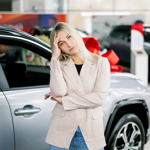 Nachdenkliche Frau wählt neues Auto im Ausstellungsraum des Autohauses